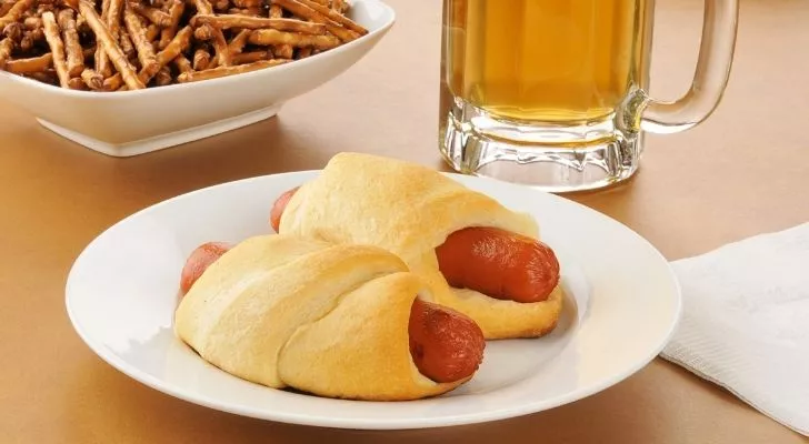 Two pigs in a blanket, a beer and some pretzels