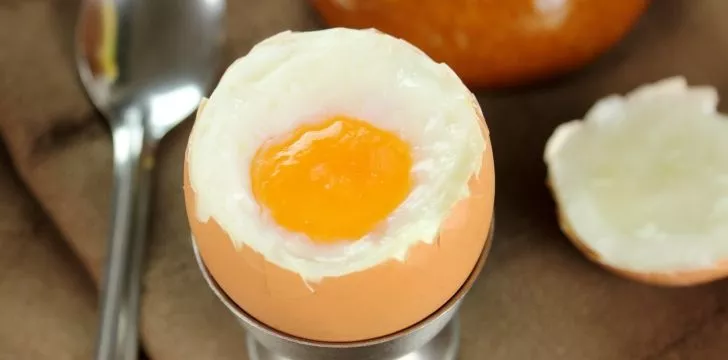 A hard boiled egg in an egg cup with slightly runner yolk.
