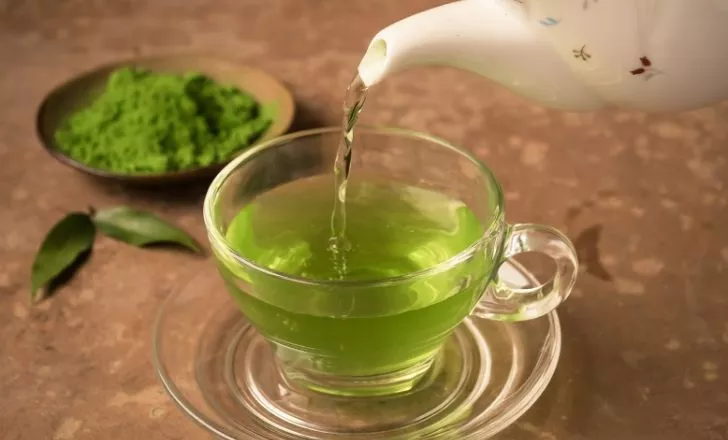 A hot pot pouring green teas into a cup
