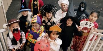A group of children on a doorstep wearing a variety of Halloween costumes