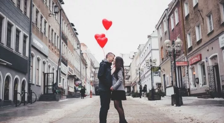 A romantic picture of a couple with red heart balloons love them