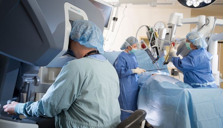 Doctors utilizing a robotic machine that conducts surgical operations.