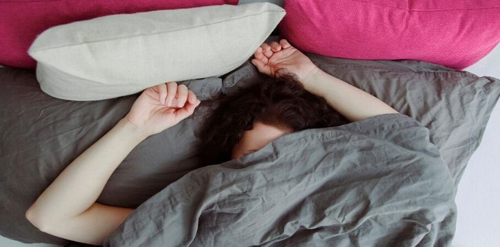 A restless woman sleeping covering her face with the duvet