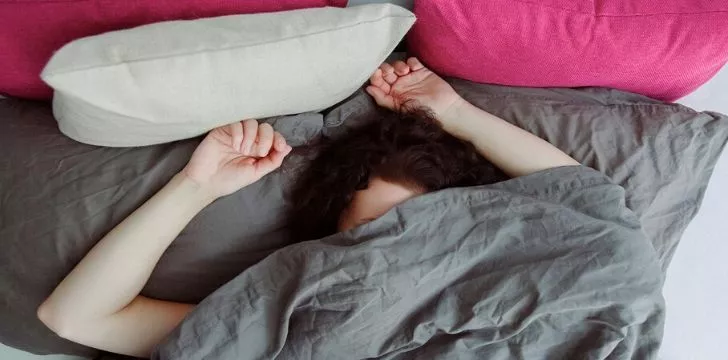 A restless woman sleeping covering her face with the duvet