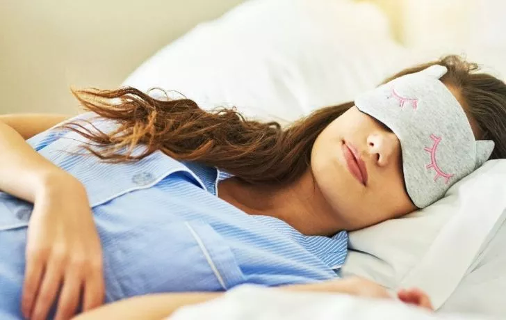 A woman happily sleeping wearing a face mask