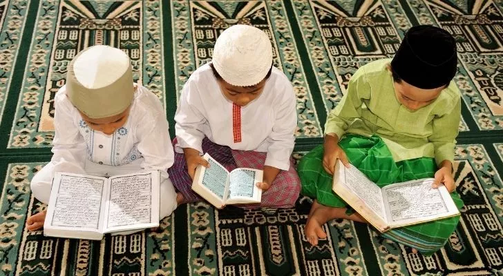 Three children studying the Qu'ran