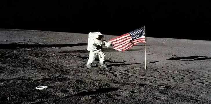 Neil Armstrong standing next to the American flag on the moon