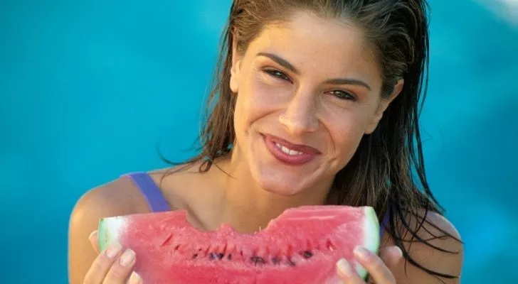 A healthy woman smiling and eating a delicious slice of watermelon