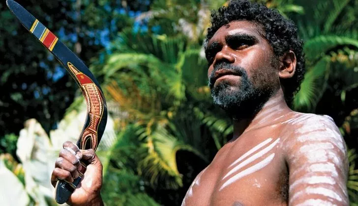 An native holding a boomerang in his right hand