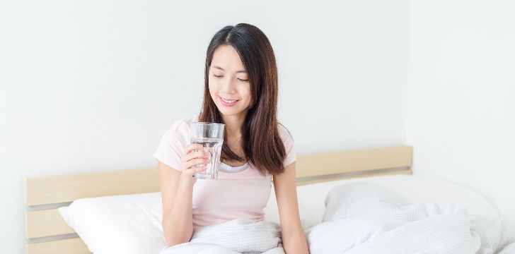 A woman in bed drinking water