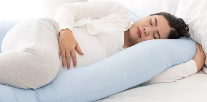 A woman sleeping on her side rubbing her belly