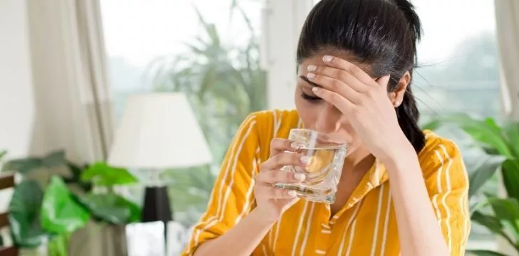A woman with a headache drinking water