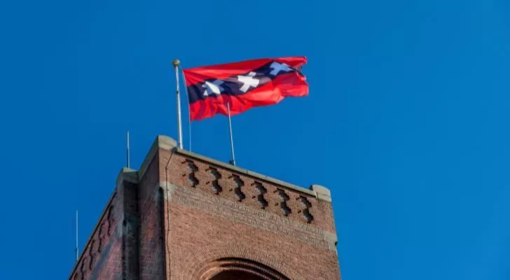 The Amsterdam flag flying above an old tower