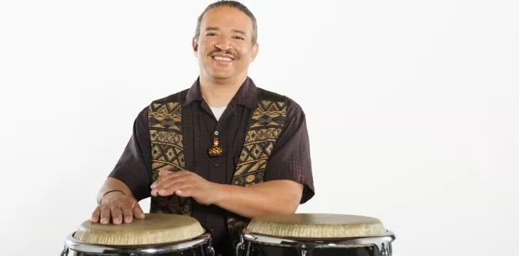 A man smiling behind a pair of Bongo drums.