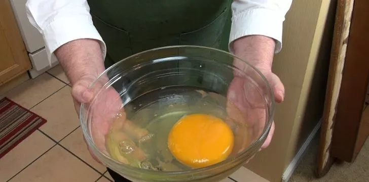 A large ostrich egg cracked open and poured into a bowl