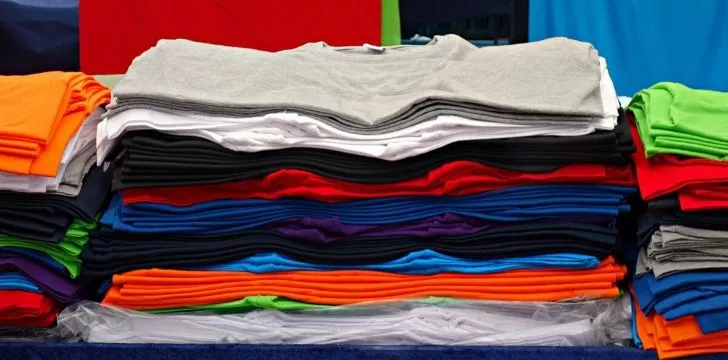 A big pile of different colored t-shirts