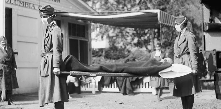 Two nurses carrying a sick man on a stretcher