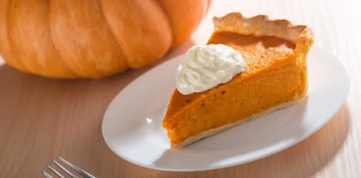 A slice of pumpkin pie with a dollop of cream on top