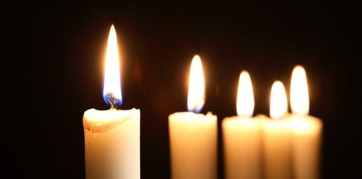 5 simple tall white candles lit in the dark