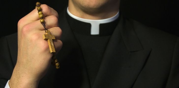 A priest holding a cross necklace