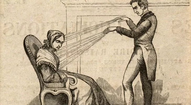 A man practicing animal magnetism on a woman sat on a chair