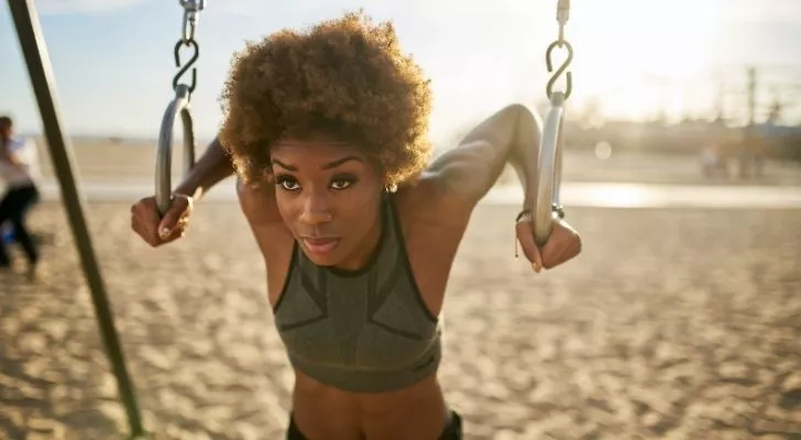 A woman balancing her weight off the ground on two chain hoops