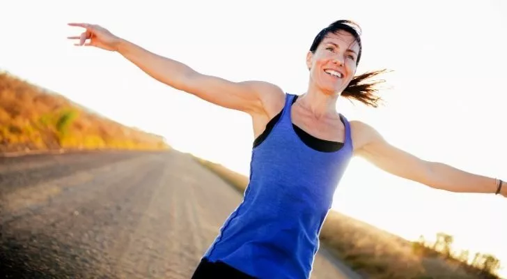 A runner with her hands open wide and smiling
