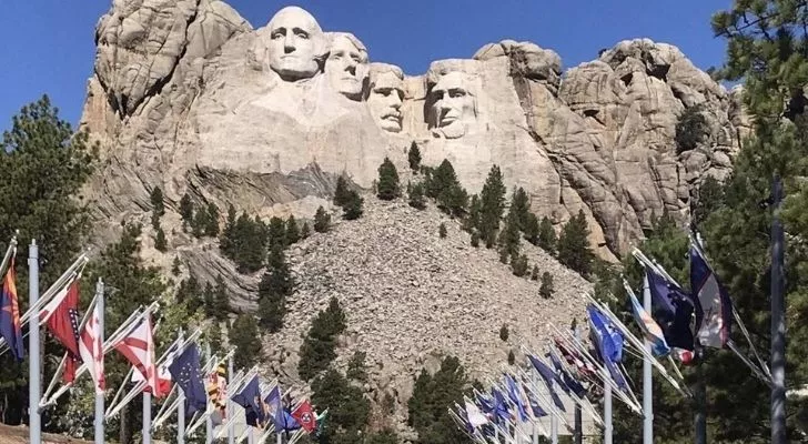 Mount Rushmore with flags in front of it