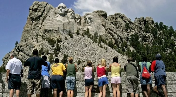 A line of visitors looking up to Mount Rushmore