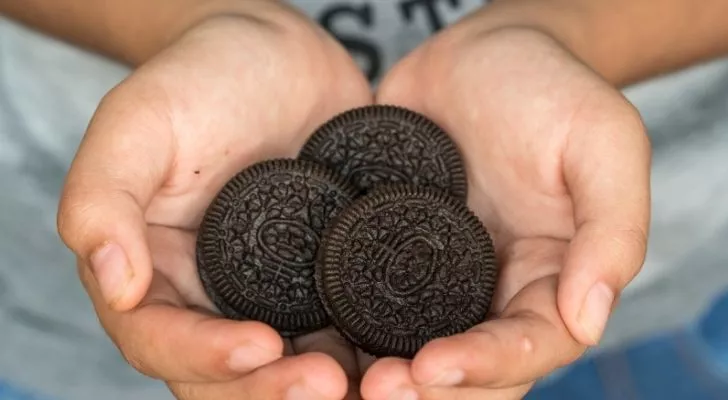 Someone with a bunch of yummy Oreos in her hands