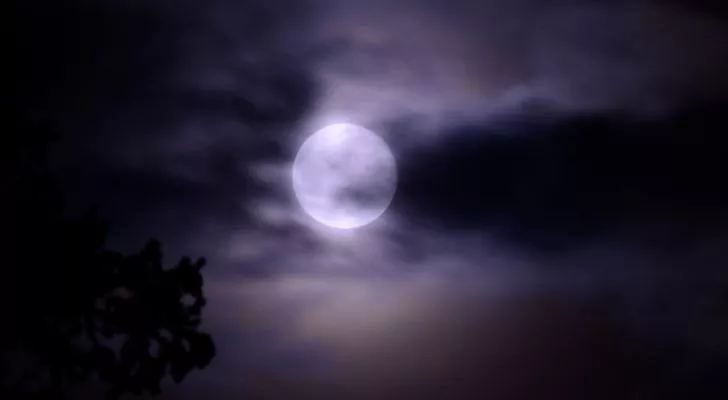 A picture of the moon from Earth with a chilly cloudy sky