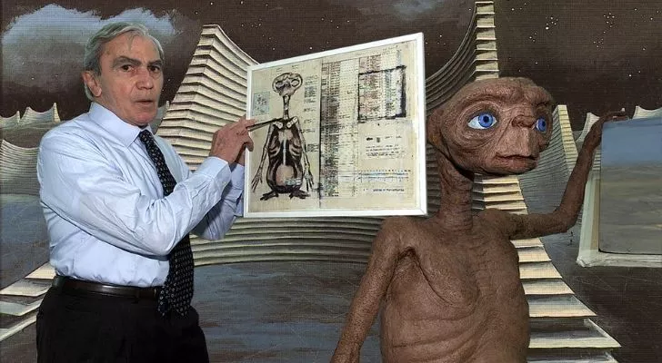 A picture of Carlo Rambaldi holding an illustration of E.T.