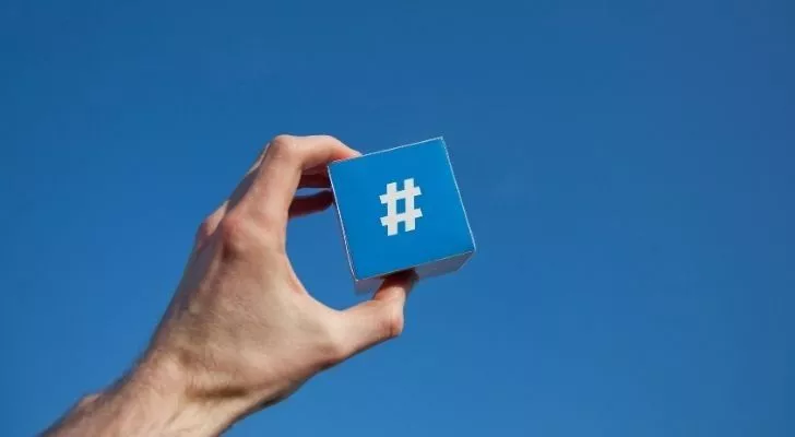 Someone holding a blue block with a white hashtag on it