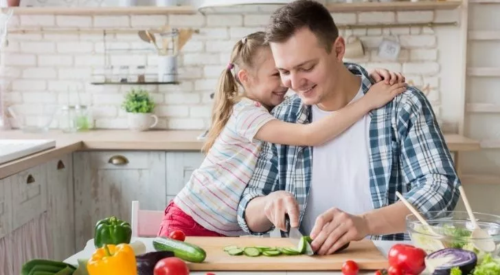 Healthy father and daughter hugging and cooking in the kitchen