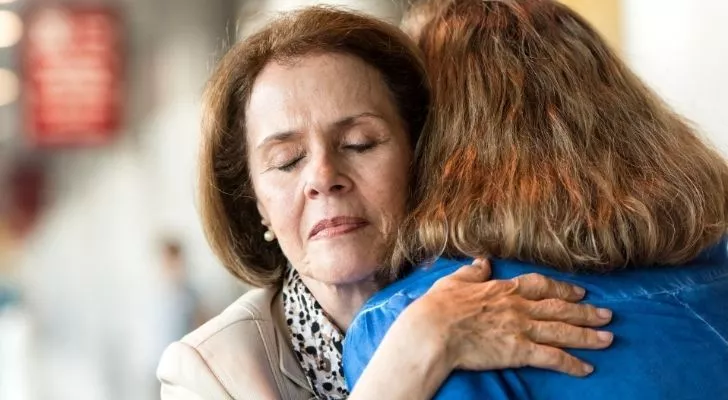 A stressed woman receiving a hug to help her feel better