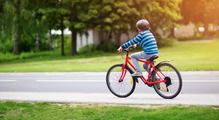 A kid riding a red bicycle