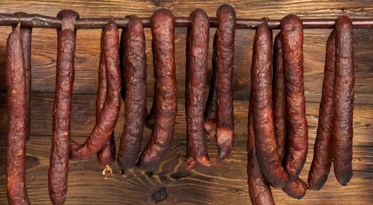 Lots of brown sausages hanging from a pole