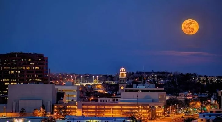 An orange worm moon shining above a city