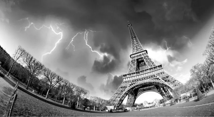 A dramatic photo of the Eiffel Tower with lightning in the sky