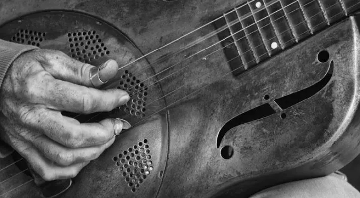 A black and white photo of someone playing the blues on a guitar