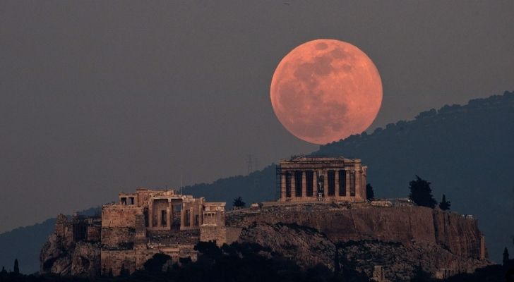 A full pink moon in the sky above ancient ruins