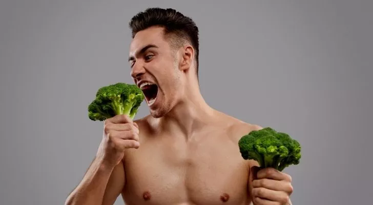 A strong guy eating broccoli