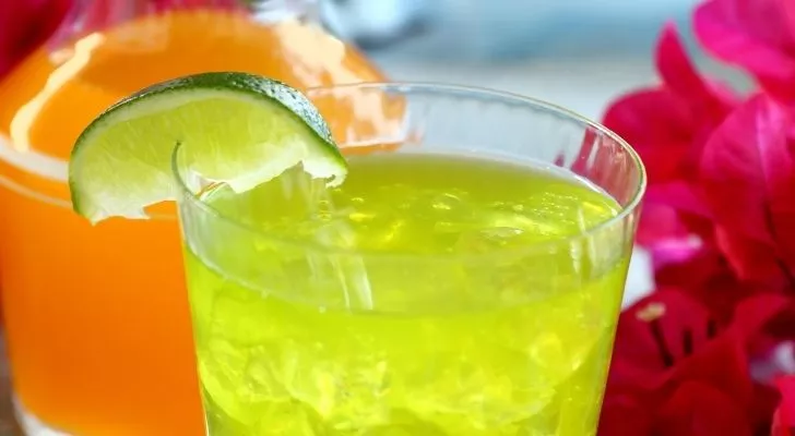 A lime drink with a lime wedge on the rim of the glass