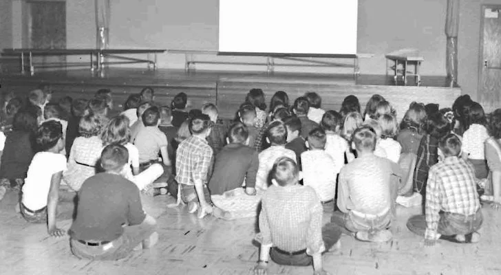 Children watching a movie on a projector in a fallout shelter