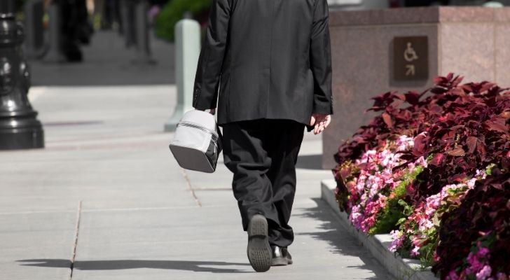 A guy in a suit walking down the Main Street with a lunch box