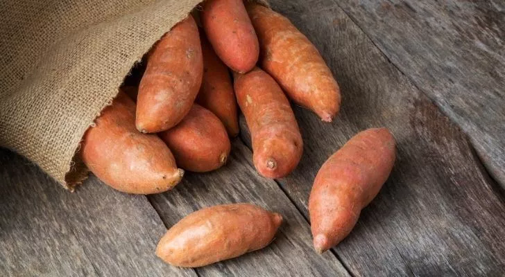 Sweet potatoes scattered across wooden floor boards