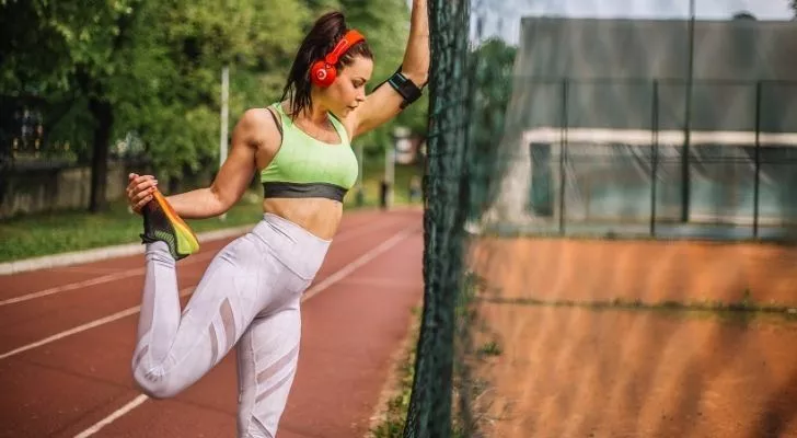 A woman stretching and listening to her favourite tunes on her headphones