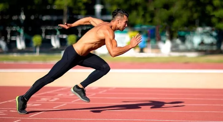 Someone sprinting with his top off and using lots of muscles