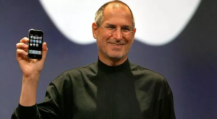 Steve Jobs elinde bir iPhone tutuyor