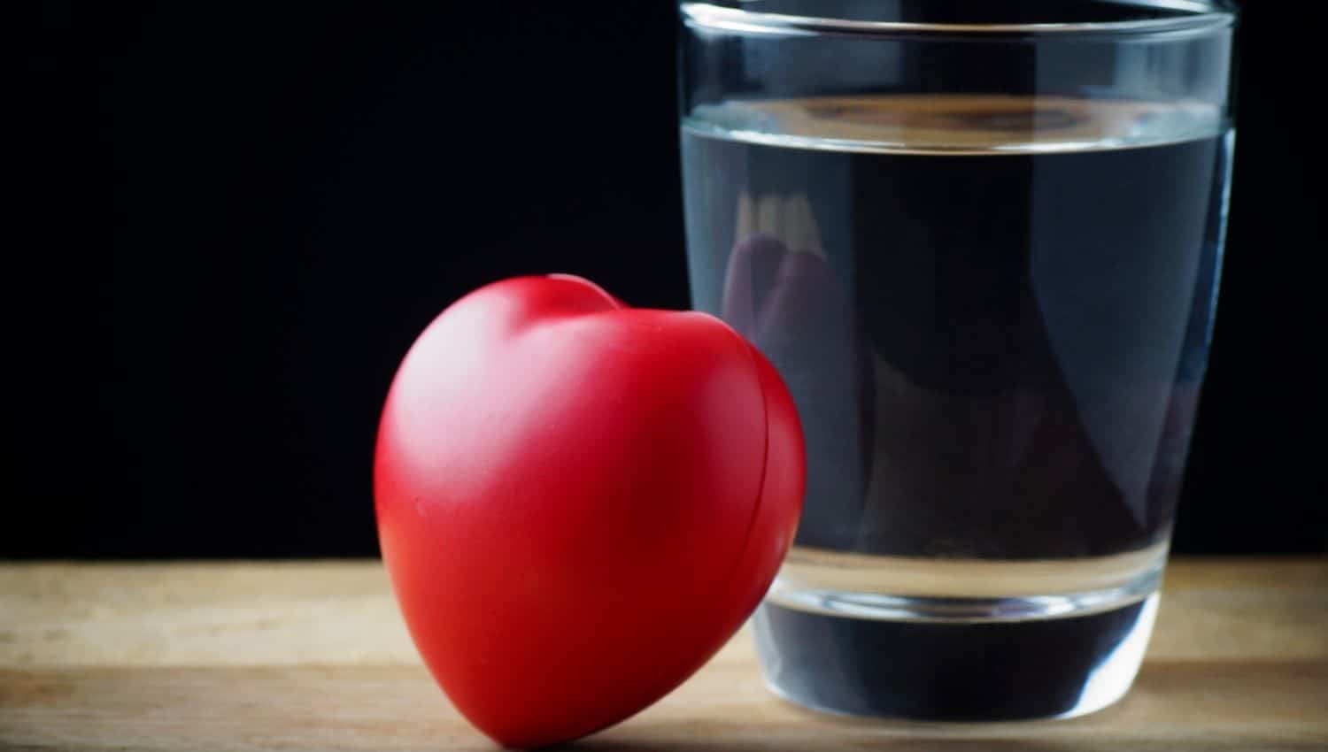 A glass of water next to a heart-shaped stress ball